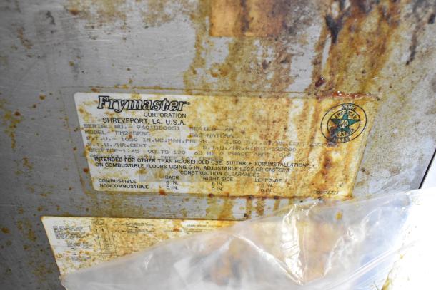 Frymaster FM245ESC fryer label, shows model, serial number, and BTU info on a rusted stainless steel surface.