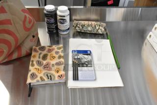 Lot of art supplies including DecoArt Americana acrylic paints, drawing pad, colored pencils, brushes, and sketchbook.