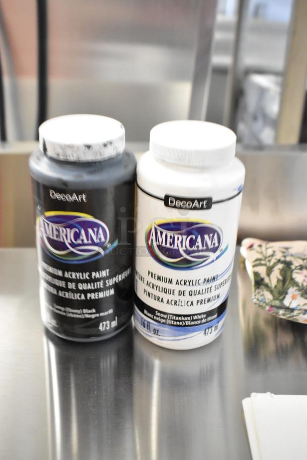 DecoArt Americana acrylic paints, 473 ml bottles in Black and Snow White, on a metallic surface.