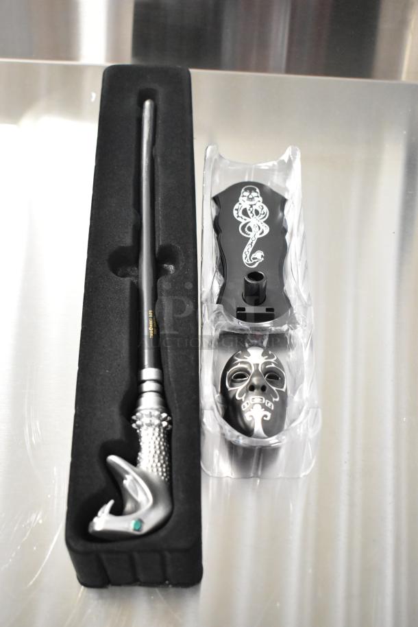 Harry Potter wand and Death Eater mask set in box, featuring detailed wand handle and decorative mask design.