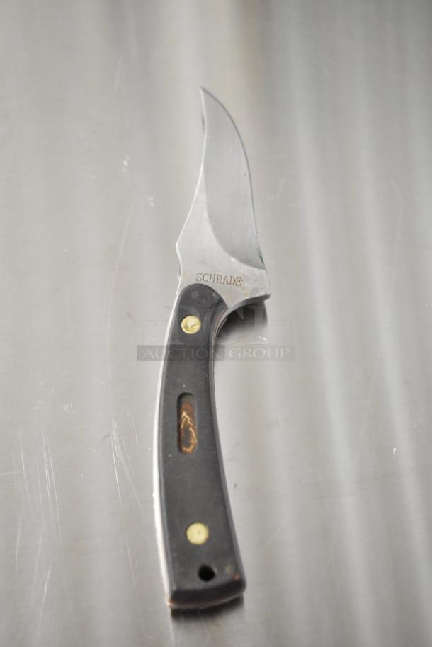 Schrade 1520T knife with a stainless steel blade and black handle, visible wear marks, "Schrade" engraved.