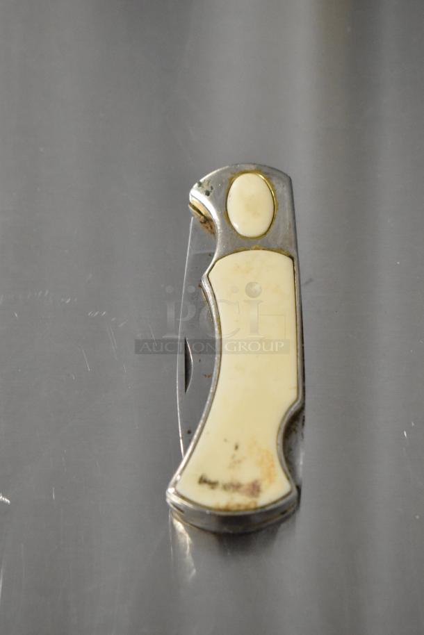 Vintage pocket knife with cream handle and visible wear, marked "Camillus 440." Metal accents. Collectible condition.