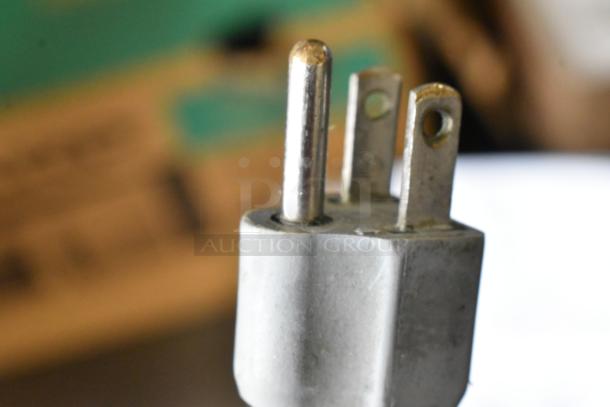 Close-up image of a three-pronged plug for the Bizerba SE 12 D US Meat Slicer, metal casing visible.