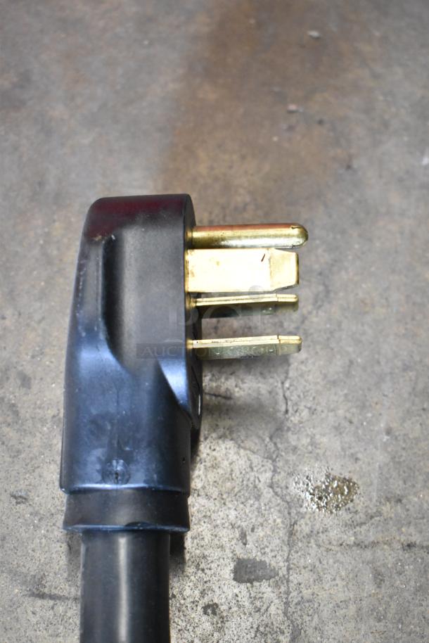 Close-up of a power plug for Fri-jado TDR 7 P rotisserie oven, showing three gold prongs and black casing.