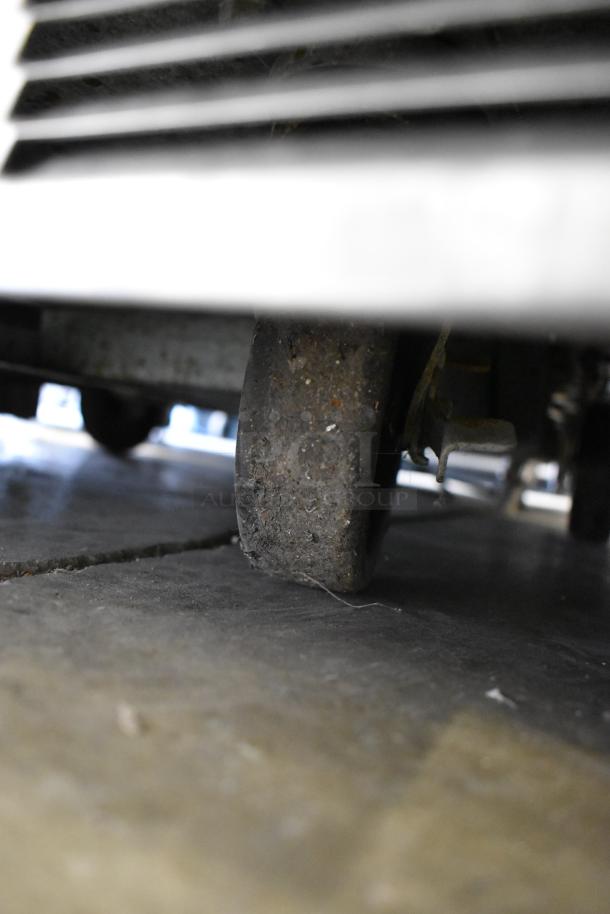 Close-up of casters on a Delfield stainless steel commercial prep table, showing wear and sturdy construction.