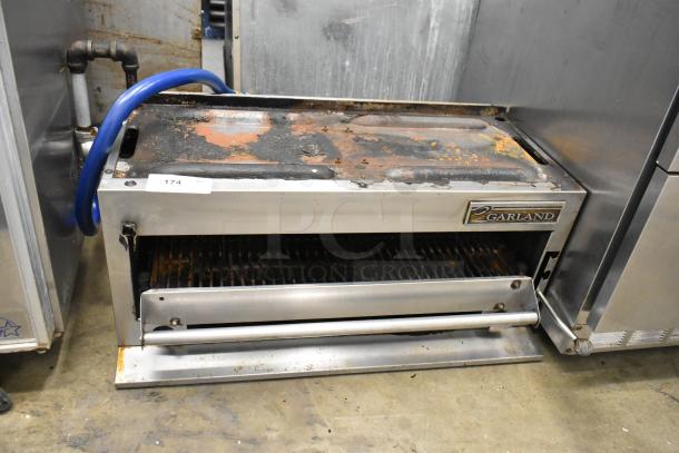 Garland stainless steel commercial gas-powered cheese melter with rust and wear. Garland logo visible, tag number 174.