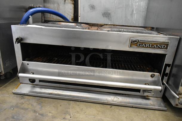 Garland stainless steel commercial gas cheese melter, used condition, visible wear, Garland logo on front panel.