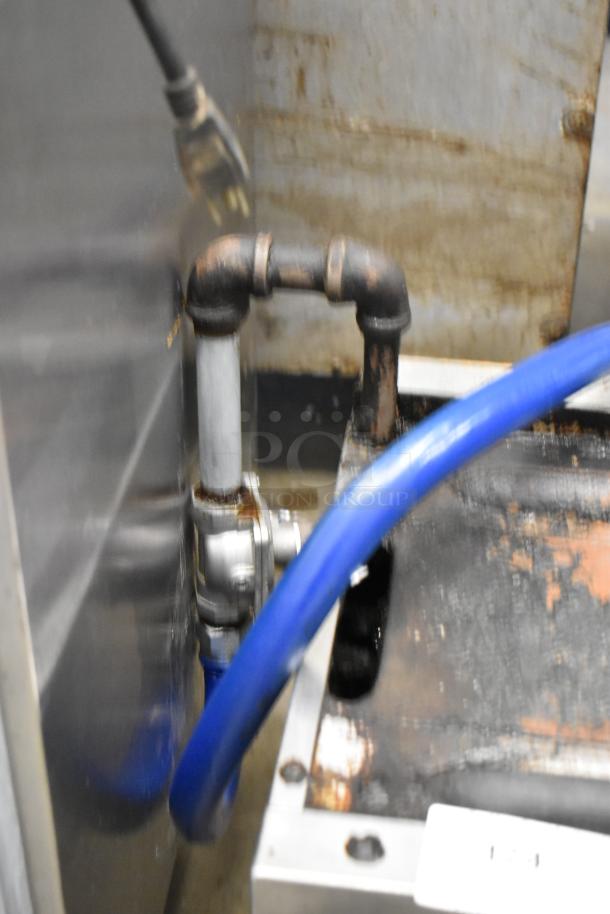 Garland stainless steel cheese melter, gas-powered, commercial-grade, showing connectors and pipes with signs of usage.