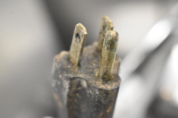 Close-up image of a worn three-prong plug from a Vollrath Cayenne Panini Press, showing signs of rust and use.
