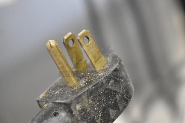 A close-up of a dusty electrical plug for a Silver King SKR27 undercounter cooler, showing three brass prongs.
