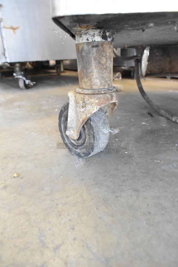 Rusty commercial caster of a Taylor 342D-27 stainless steel frozen beverage machine on a concrete floor.
