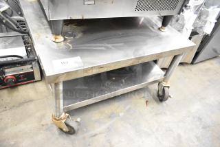Stainless steel equipment stand with metal undershelf on commercial casters, marked with tag "192". Shows wear.