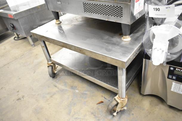 Stainless steel equipment stand with metal under shelf, on commercial casters, minor wear visible, ideal for kitchen use.