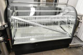 Metal commercial floor-style dry display case merchandiser with curved glass front, two-tier wire shelving, and black base.