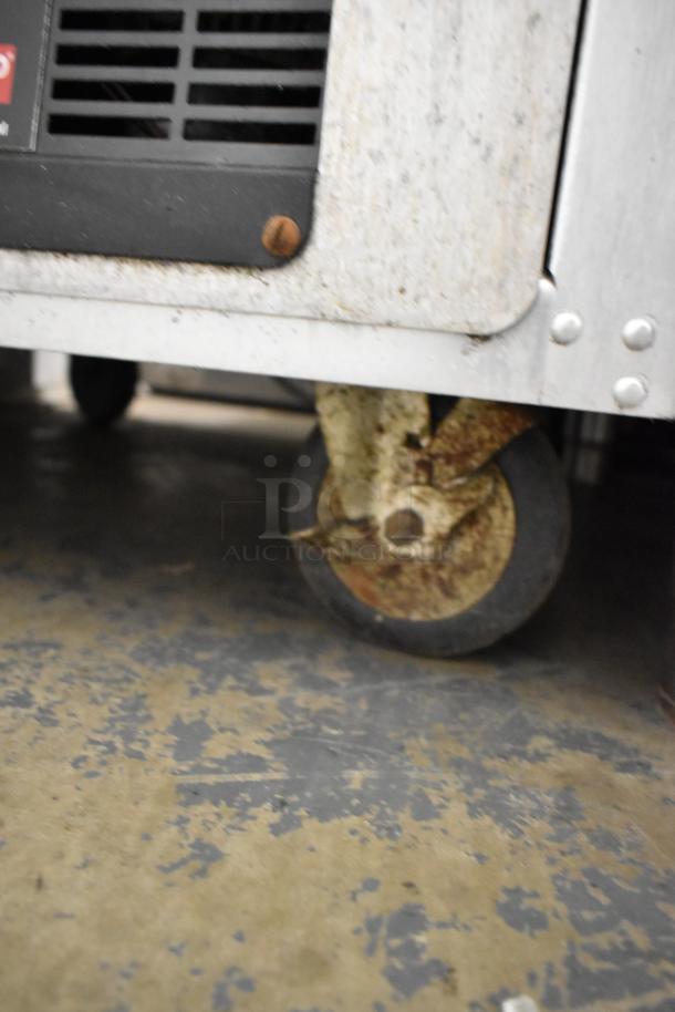 Metro FlavorHold C199 heated holding cabinet on commercial casters, showing a worn metal caster and rust on the wheel housing.