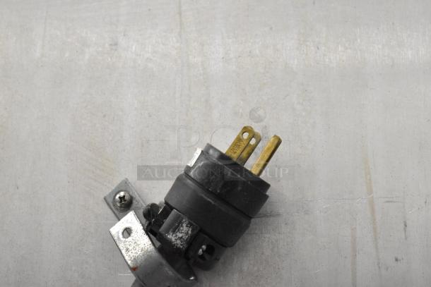 Metro FlavorHold C199 Heated Holding Cabinet plug close-up. Black and metal plug in used condition on a light surface.