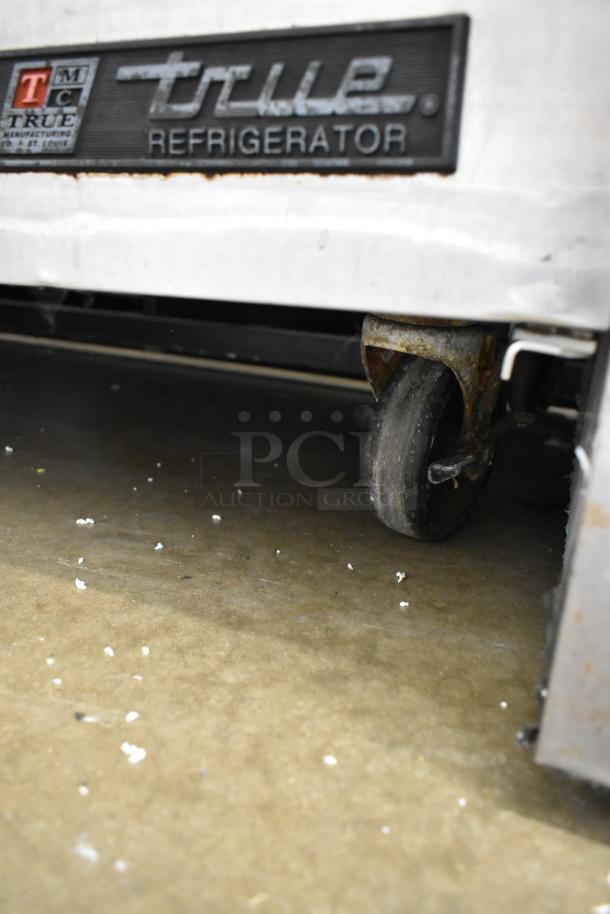 True TSSU-72-30M-B-ST stainless steel prep table on commercial casters, missing lid, label indicating "True Refrigerator."