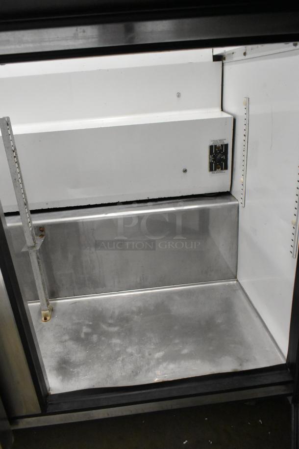 True TSSU-72-30M-B-ST stainless steel sandwich prep table; missing lid, on casters. 115V, 1 phase. Interior view.