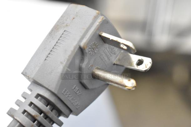A close-up of a Cecilware Panini Press power plug, showing a standard three-prong configuration. Plug is labeled HDX.