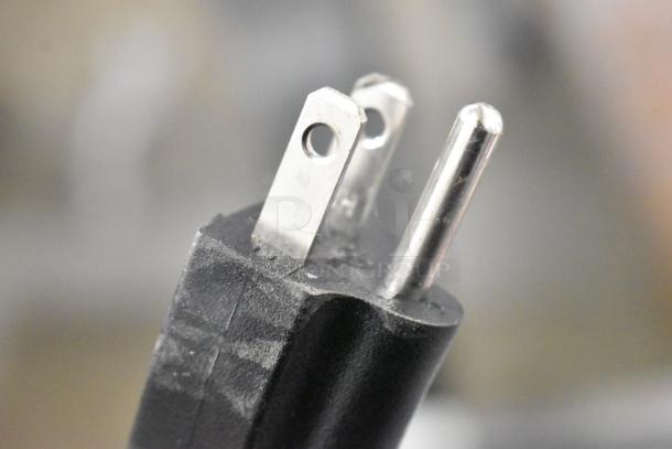 Close-up of a power plug for the KoolMore KM-CGD-8HP ice cream display case, showing metal prongs and black casing.
