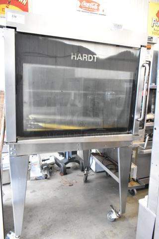 Hardt Inferno 4500 stainless steel commercial rotisserie oven, natural gas, with skewers on metal legs, in used condition.