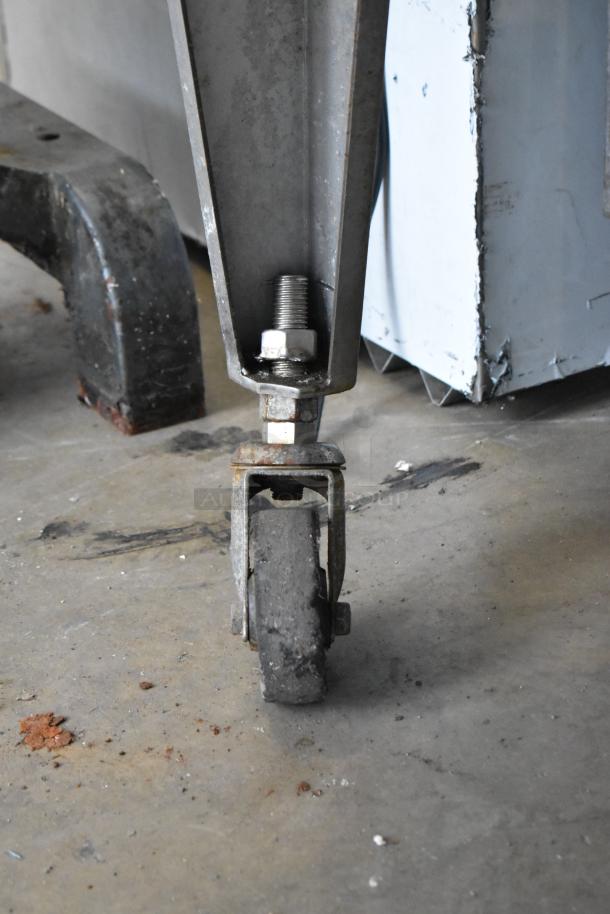 Stainless steel caster on a Hardt Inferno 4500 rotisserie oven. Rugged, commercial-grade, showing wear.