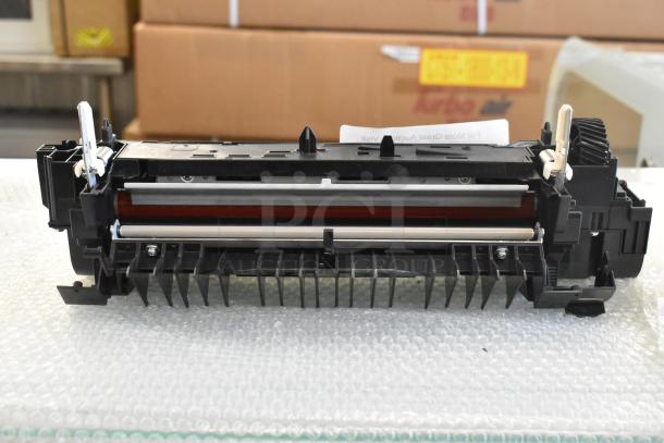 Black printer cartridge, key components visible, good condition, resting on bubble wrap, labels not discernible.