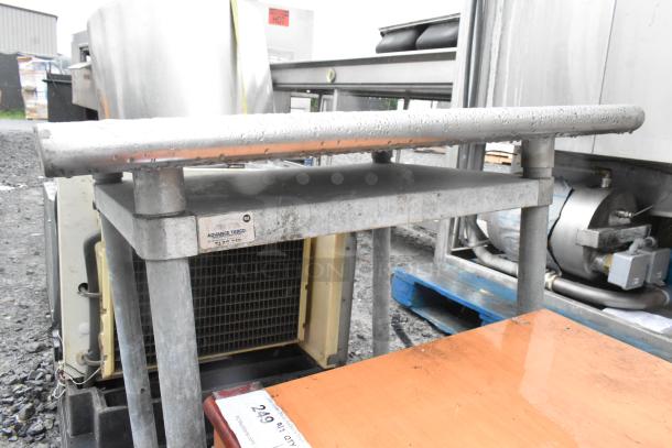 Stainless steel table with sturdy frame, visible brand tag "Advance Tabco", in used condition, outdoor setting.