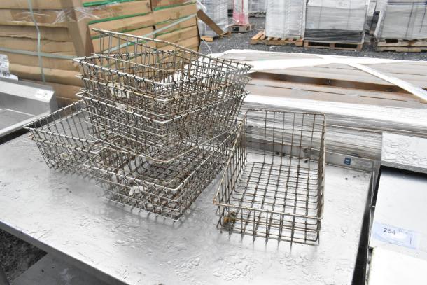 Stainless steel table with metal under shelf, includes several metal baskets. Table shows surface wear.