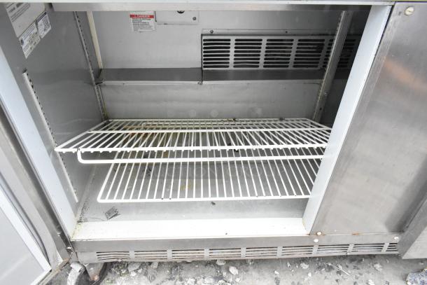 Beverage Air SPE60-16 sandwich salad prep table interior, stainless steel with wire shelves, on commercial casters.