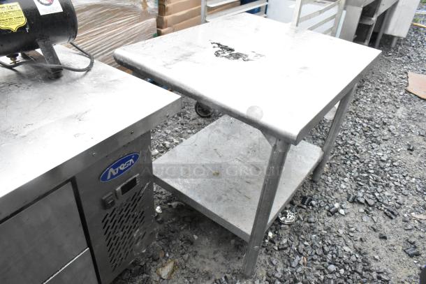 Stainless steel table with metal under shelf, used condition, sturdy design, suitable for industrial or kitchen use.