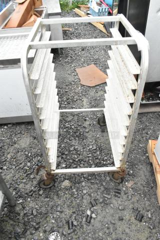 Metal commercial transport pan rack with multiple shelves on heavy-duty casters, visible wear and rust.