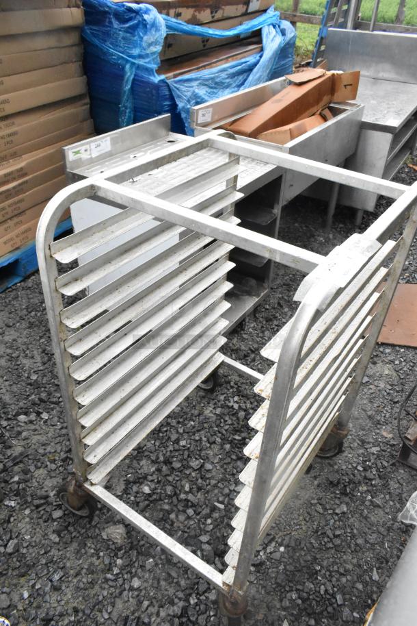 Metal commercial transport pan rack on casters, showing a sturdy frame with multiple slotted shelves and visible wear.