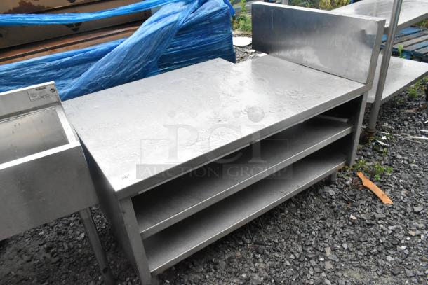 Stainless steel equipment stand with two under shelves, durable, slight surface wear, ideal for kitchens or industrial use.