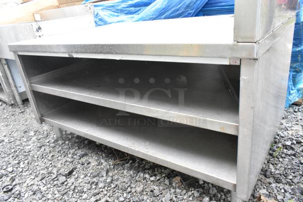Stainless steel equipment stand with two under shelves, minor wear, ideal for kitchen storage and organization.