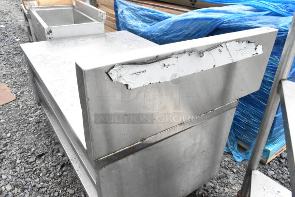 Stainless steel equipment stand with two under shelves, showing visible wear. Ideal for kitchen or industrial use.