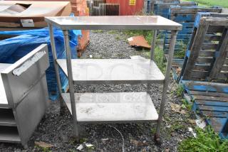 Stainless steel 3-tier shelving unit on commercial casters, showing minor wear, ideal for storage or commercial use.