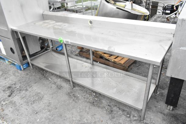 Stainless steel table with under shelf and back splash, used condition, minor wear, ideal for commercial kitchens.