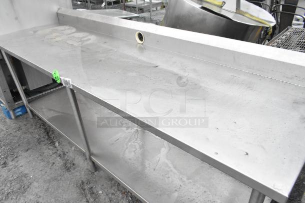 Stainless steel table with under shelf and back splash, lightly worn condition, features durability and practical design.