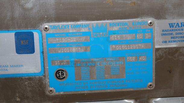 NEW Taylor Soft Serve Freezer Model Y150-12, detailed label showing model, serial number J1016855, voltage, and refrigerant info.