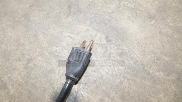 Power plug of new Taylor Soft Serve Freezer, Model Y150-12. Standard three-prong design, slightly dusty, on concrete surface.
