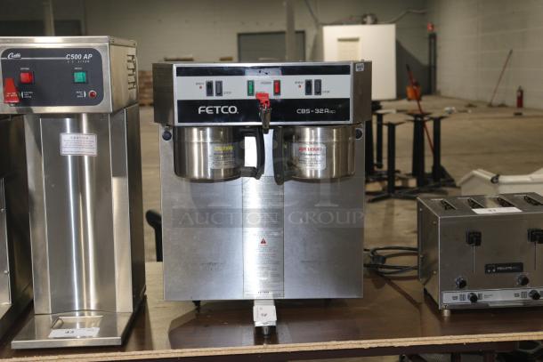 Used Fetco CBS-32Aap dual coffee brewer machine in stainless steel; features brew/stop buttons; 120/208-240V; visible caution labels.