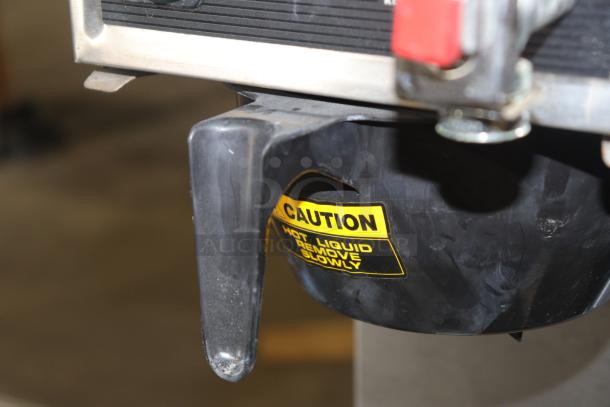 Brewmatic M-90 coffee brewer component with a "Caution: Hot Liquid, Remove Slowly" label visible.