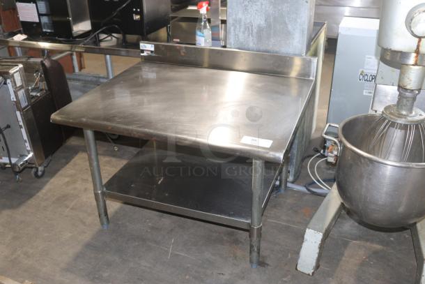 Brand new stainless steel commercial table with backsplash and lower shelf, pristine condition, ideal for kitchen use.