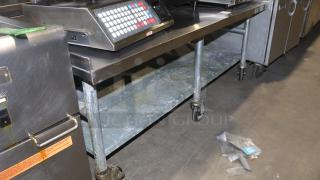 61" stainless-steel counter with casters, ideal for baking or cooking. Features sturdy metal construction and spacious lower shelf.