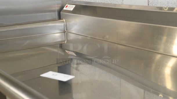 48" stainless-steel counter for baking, cooking, or storing. Durable, reflective surface, signs of light use, with label visible.