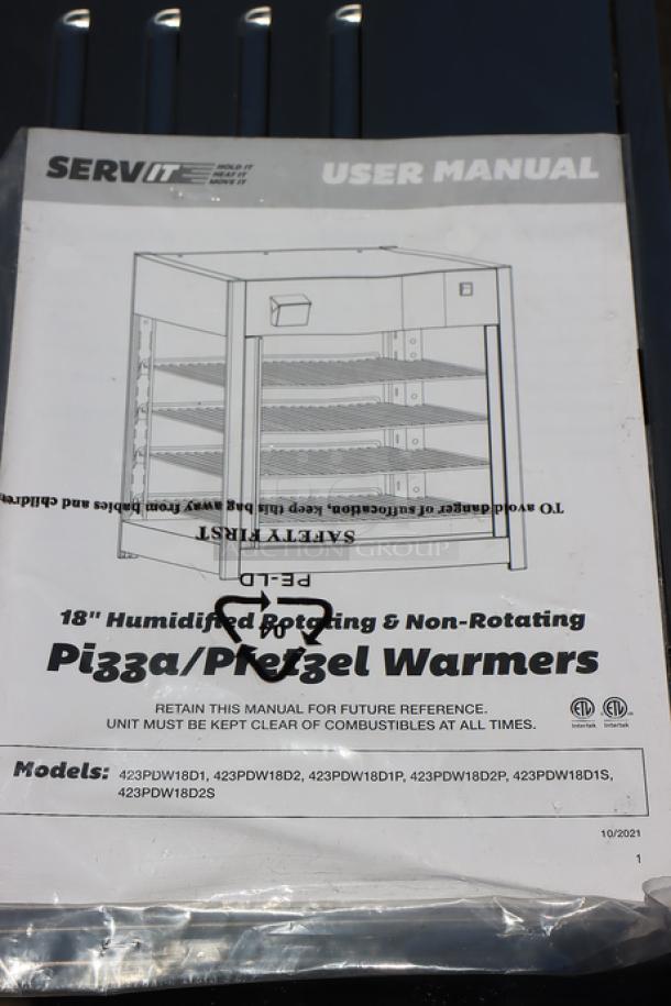 ServIt PDW18D2S user manual on black surface. Manual shows illustration of 18" countertop display warmer with four shelves.