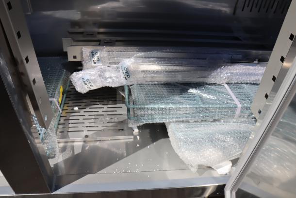 Brand new Avantco SS-3F-HC stainless steel reach-in freezer interior, shows shelves and parts wrapped in bubble wrap. Missing power cord and vents, minor scratches and dents.