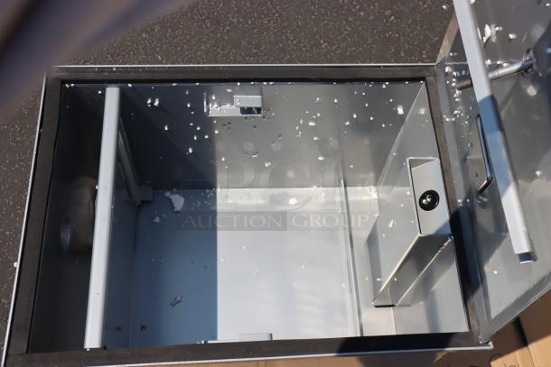 Regency 600GT15 30 lb. 15 GPM grease trap, brand new, open view, non-threaded 2" connections, some debris visible.