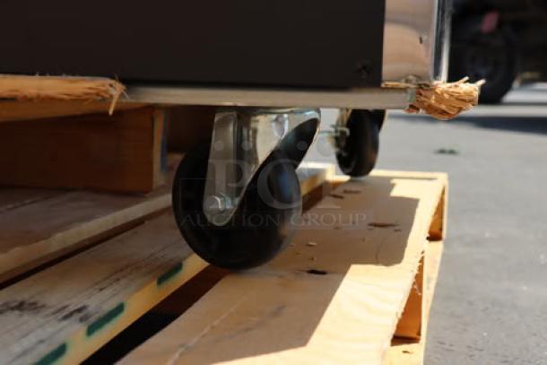 Avantco SS-UD-3R undercounter refrigerator on pallet, showing one bent caster. Stainless steel, new condition with some scratch and denting.